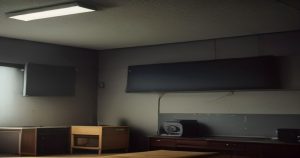 A empty community radio studio with an unattended microphone and a dark control board, dim overhead lighting